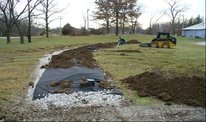 An at-grade system under construction with geotextile fabric covering the rock media.
